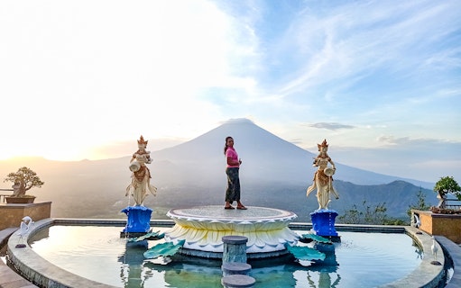 Person standing on a platform with Mount Agung in the background, Bali Fullday Private Customized Tour.