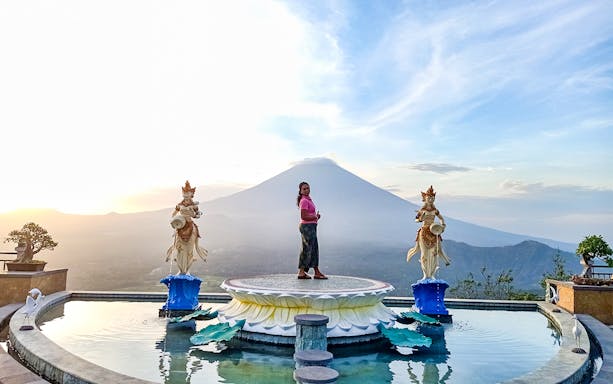 Person standing on a platform with Mount Agung in the background, Bali Fullday Private Customized Tour.