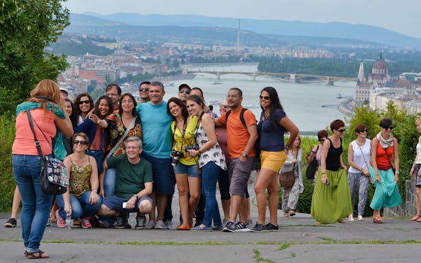 Group of tourists posing on Gellért Hill with Budapest cityscape and Danube River in the background.