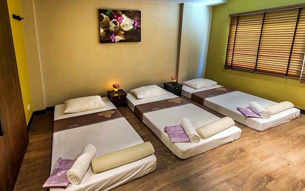 Three massage beds in a Let's Relax Thai Massage room with soft lighting.
