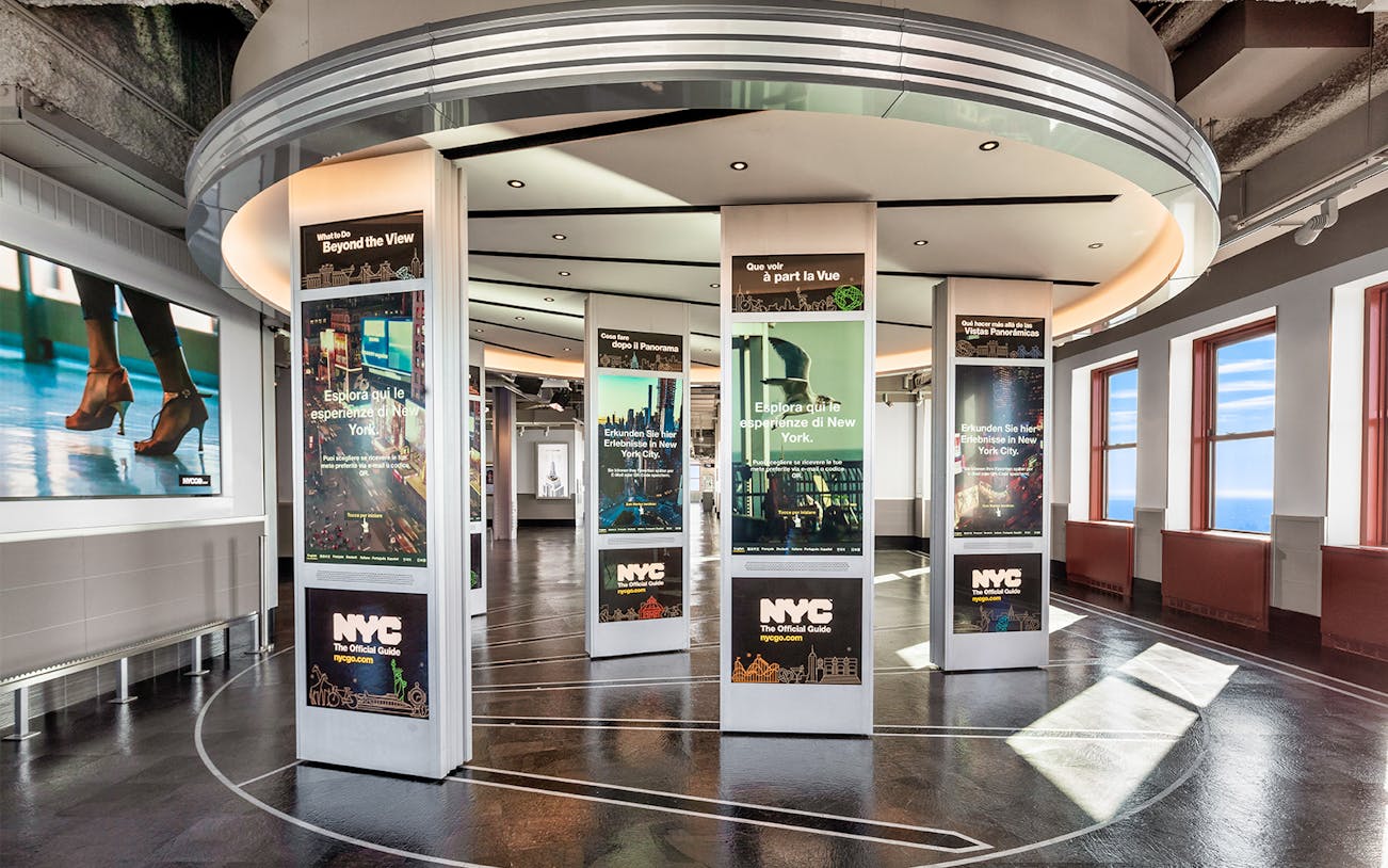 NYC Explorer Pass display area with multilingual posters at an observation deck.