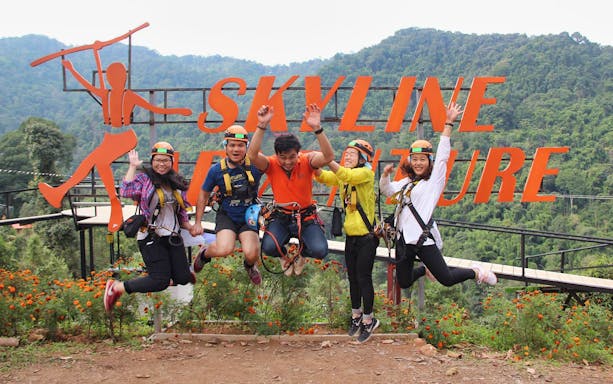 Group of people in harnesses jumping in front of Skyline Adventure sign in Phuket.