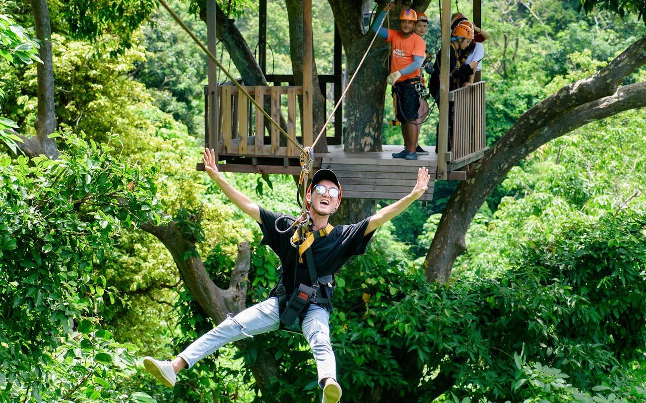 Ziplining through lush forest canopy in Phuket adventure tour.