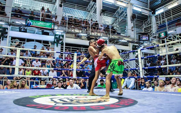 Muay Thai fighters in action at Bangla Boxing Stadium, Phuket, with a crowd watching.