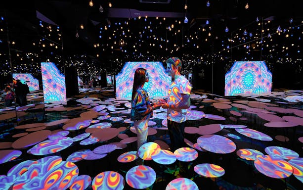 Couple in colorful, immersive light display at Tribhum Adventure Park.