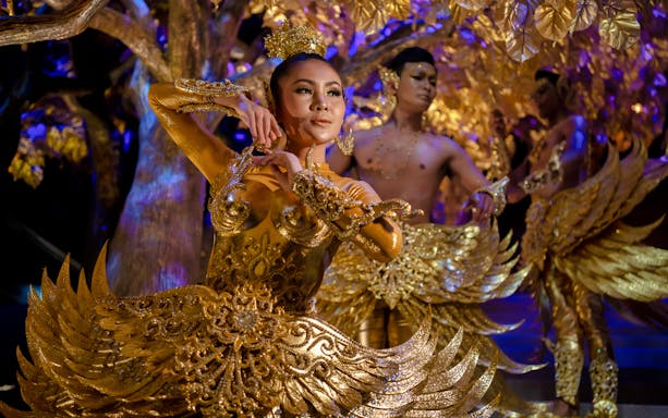 Performers in golden costumes at Tribhum: The Mystical Three Worlds Adventure Park.