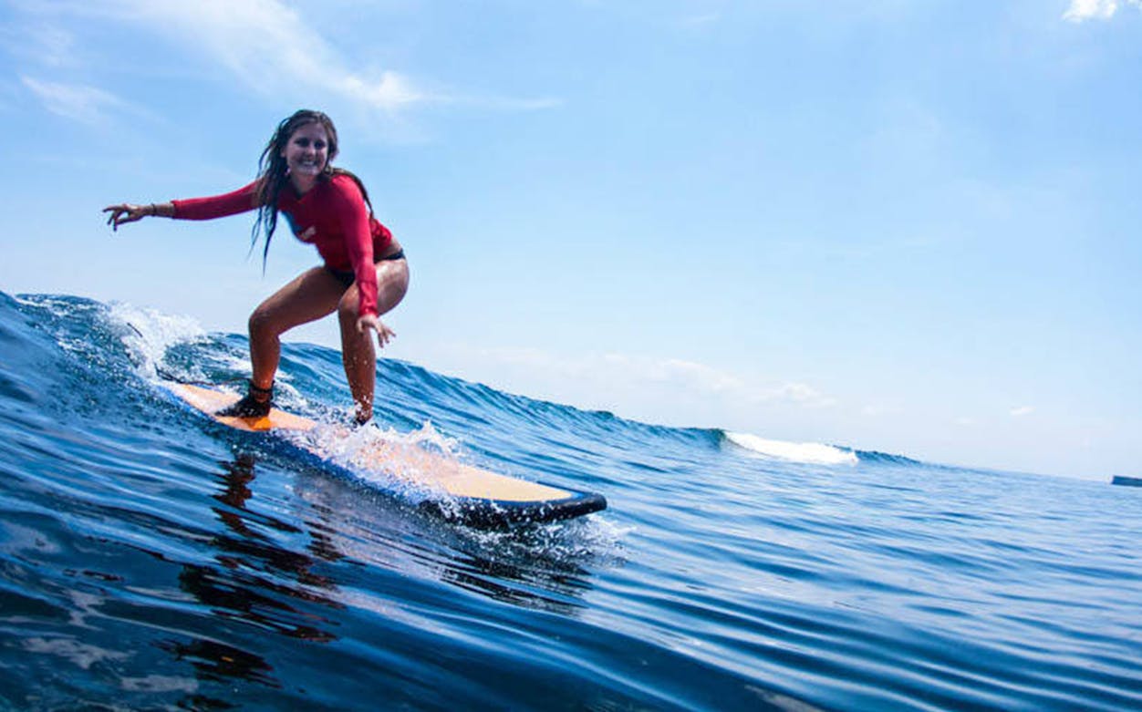 Surfer riding a wave during a Bali surf class.
