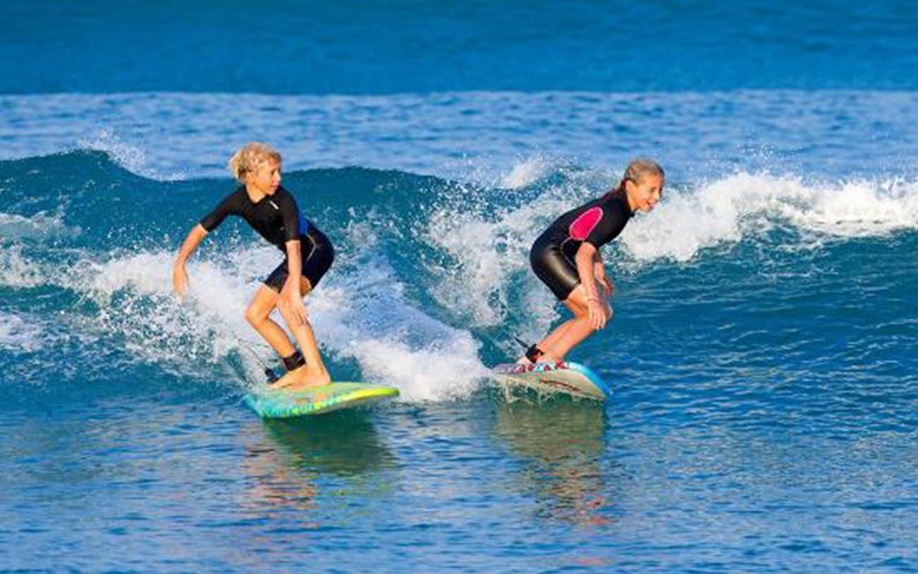 Two people surfing on waves during a Bali surf class.