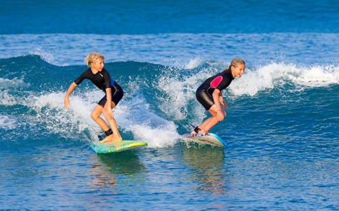 Two people surfing on waves during a Bali surf class.
