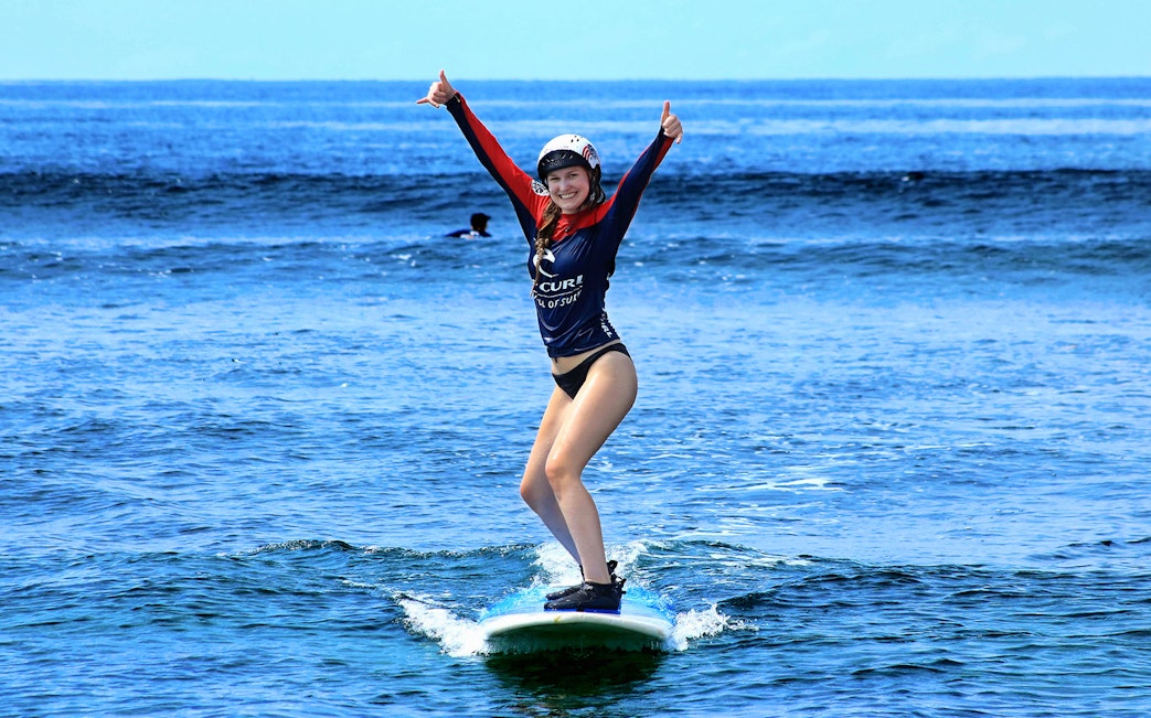 Surfer balancing on a board in Bali's ocean waves.
