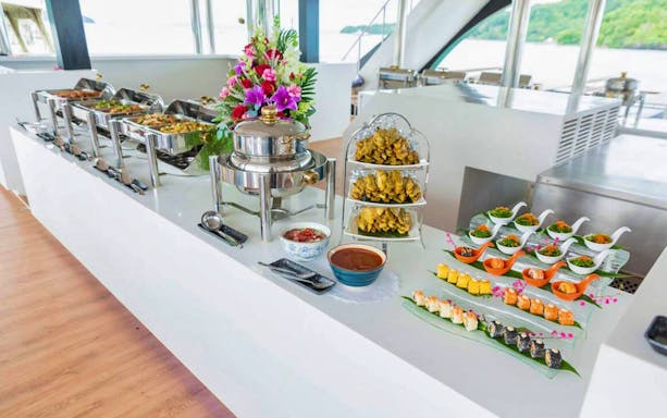 Buffet setup on Phi Phi Island tour boat with assorted dishes and floral arrangement.