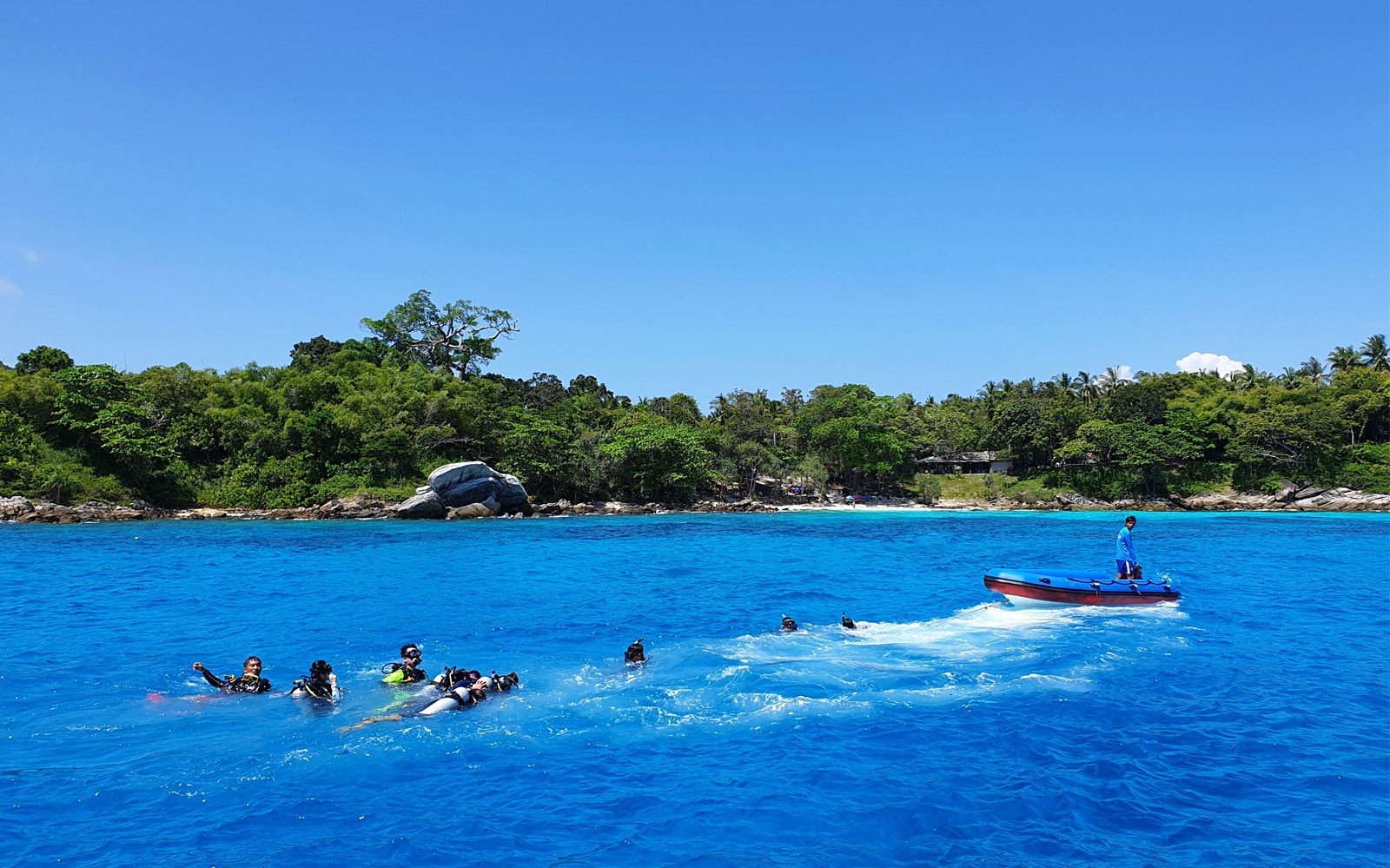 Snorkelers in clear blue water near Racha Noi island with a speedboat nearby.