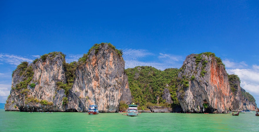 Speed boats near limestone cliffs at James Bond Island, Phang Nga, Thailand.