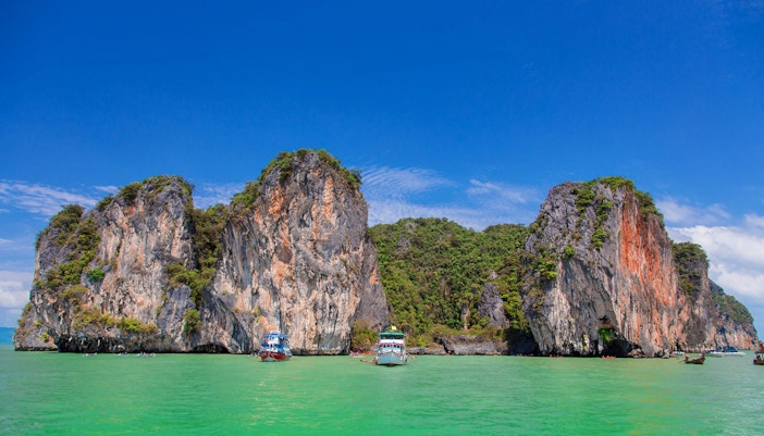 Speed boats near limestone cliffs at James Bond Island, Phang Nga, Thailand.