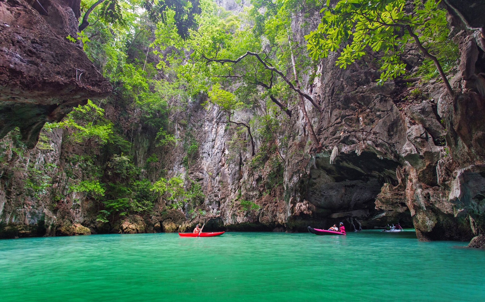 Kayakers exploring limestone cliffs and emerald waters on James Bond Island, Phang Nga.