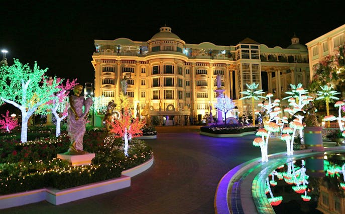 Sukhawadee House illuminated at night with colorful lights and statues in Pattaya, Thailand.