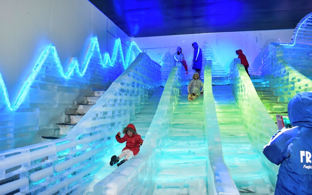Children sliding down ice slides at Frost Magical Ice of Siam.