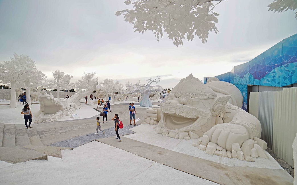 Visitors exploring Frost Magical Ice of Siam with large white sculptures in Pattaya, Thailand.