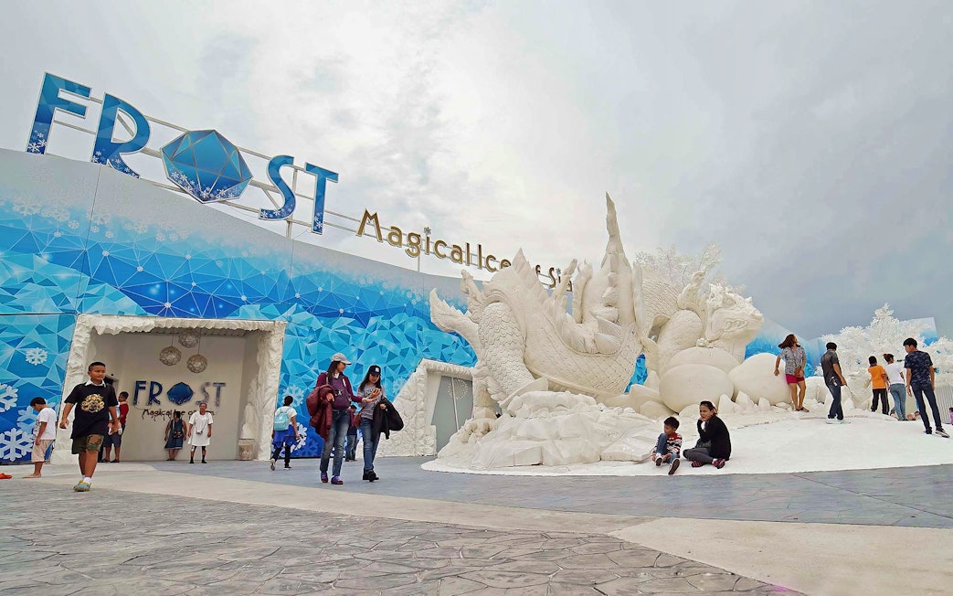 Visitors exploring Frost Magical Ice of Siam with large ice sculptures in Pattaya, Thailand.