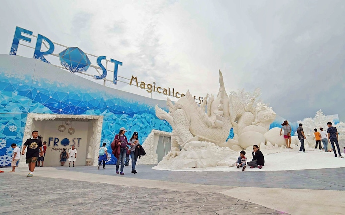 Visitors exploring Frost Magical Ice of Siam with large ice sculptures in Pattaya, Thailand.
