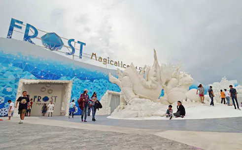 Visitors exploring Frost Magical Ice of Siam with large ice sculptures in Pattaya, Thailand.