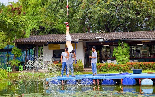 Bungy jumper hanging upside down over water at Pattaya adventure park.