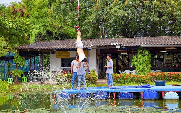 Bungy jumper hanging upside down over water at Pattaya adventure park.