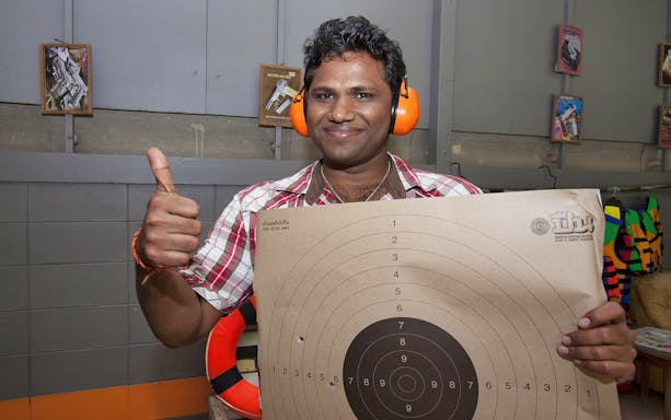 Man holding a target with bullet holes at Pattaya Shooting Park.