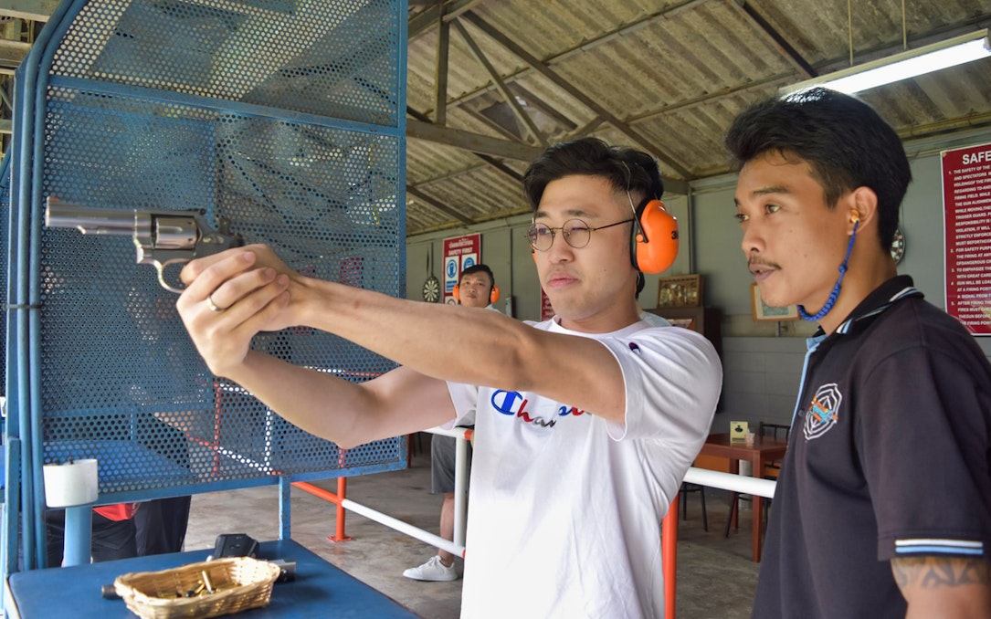 Man aiming .38 caliber revolver at Pattaya Shooting Park with instructor guidance.