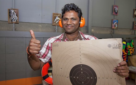 Man holding a target with bullet holes at Pattaya Shooting Park.