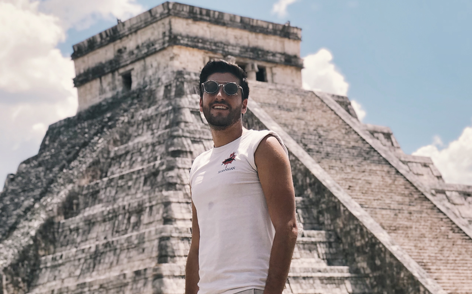 Man standing in front of El Castillo pyramid at Chichén Itzá, Mexico.