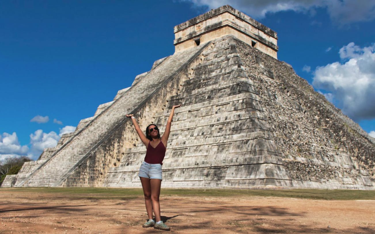 Tourist posing in front of El Castillo pyramid at Chichén Itzá, Mexico.