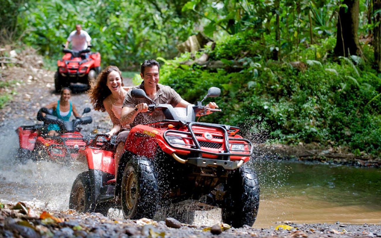 ATV riders splashing through a forest trail in Puerto Vallarta.