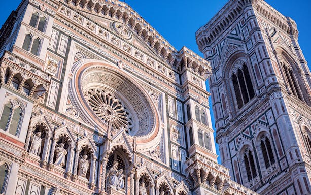 Facade of Florence Cathedral with intricate sculptures and Brunelleschi’s Dome in the background.