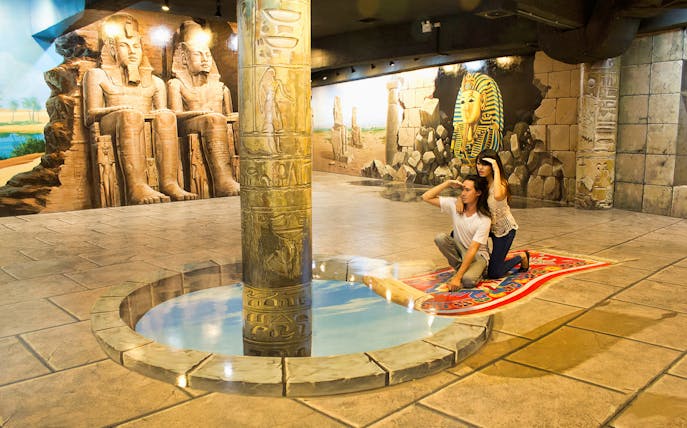Visitors on a magic carpet illusion at Art in Paradise Chiang Mai, with Egyptian murals.