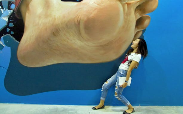 Person interacting with 3D art of a giant foot at Art in Paradise Chiang Mai.