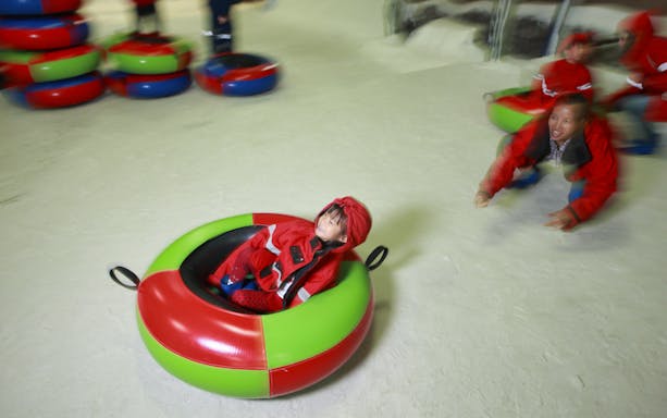 Child tubing on snow at Chiang Mai Zoo & Aquarium, Thailand.