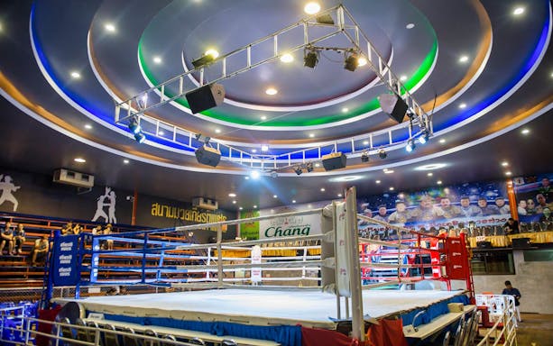 Chiang Mai boxing stadium with empty ring and colorful ceiling lights.