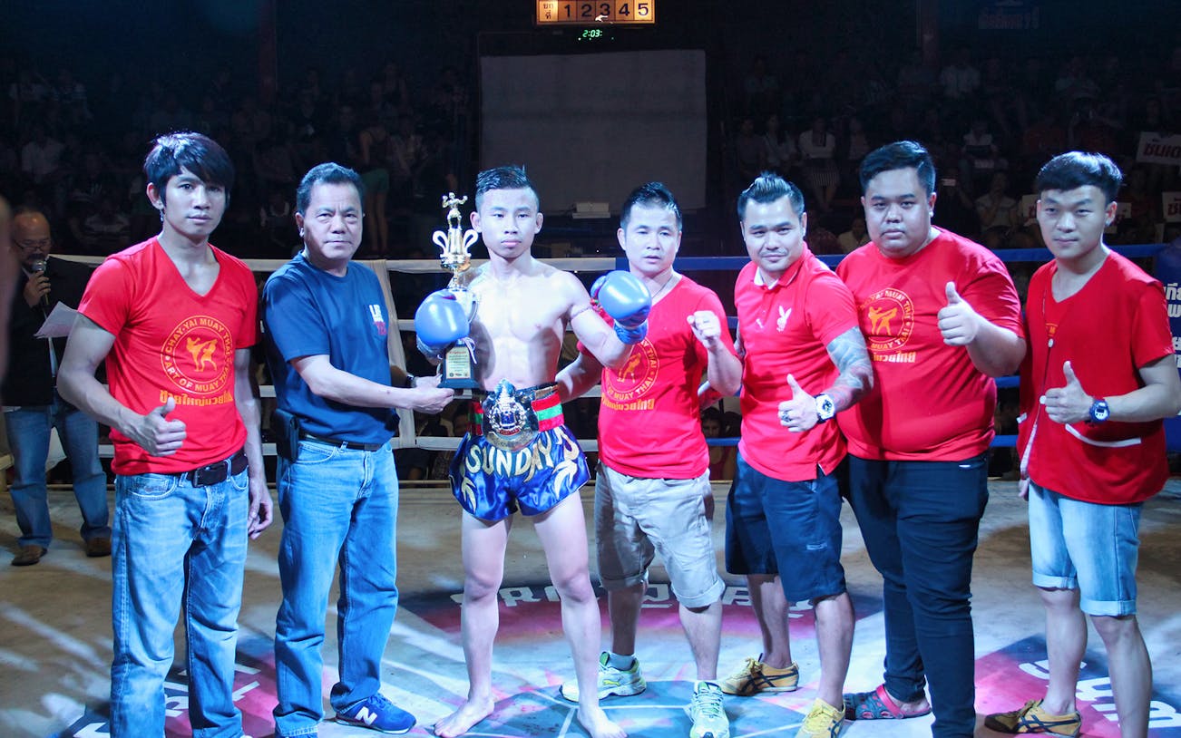 Muay Thai fighter with team at Chiang Mai Boxing Stadium.