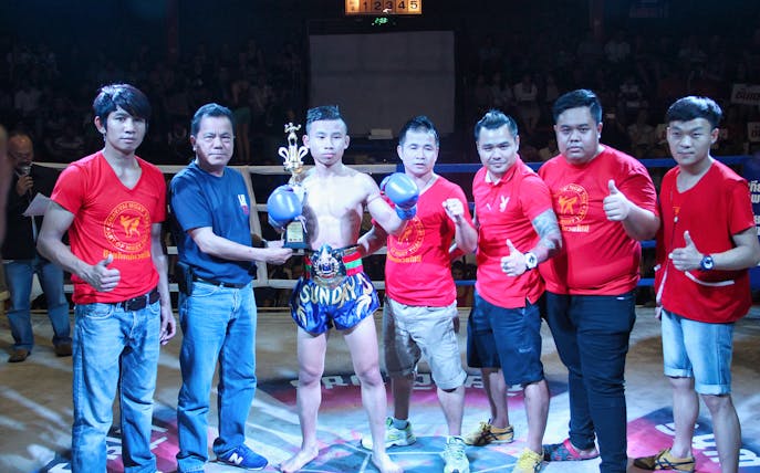 Muay Thai fighter with team at Chiang Mai Boxing Stadium.