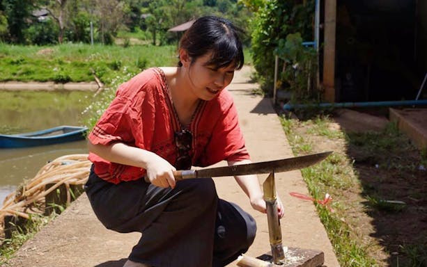 Person preparing bamboo at Ran Tong Elephant Care Experience, Thailand.