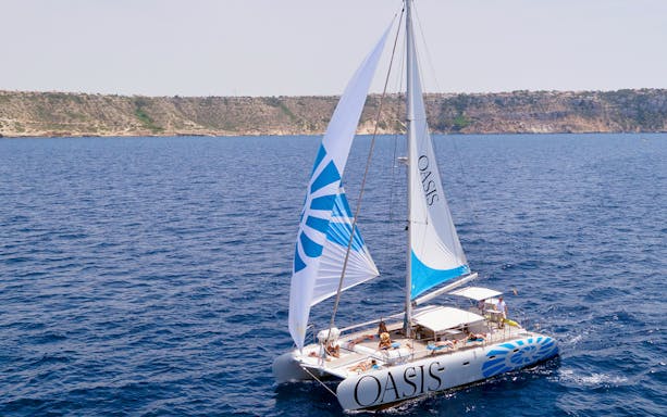 Catamaran sailing near rocky coastline during a tour with lunch.