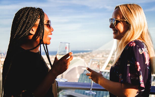 Two people enjoying wine on a rooftop with City of Arts & Sciences view.