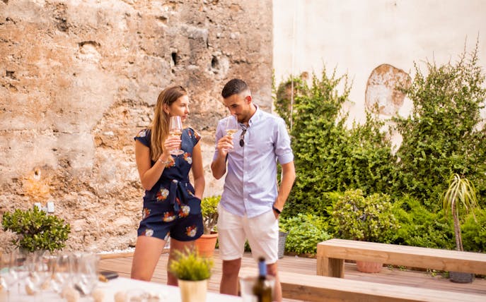 Couple enjoying wine in Valencia's Old Town 11th-century monument courtyard.