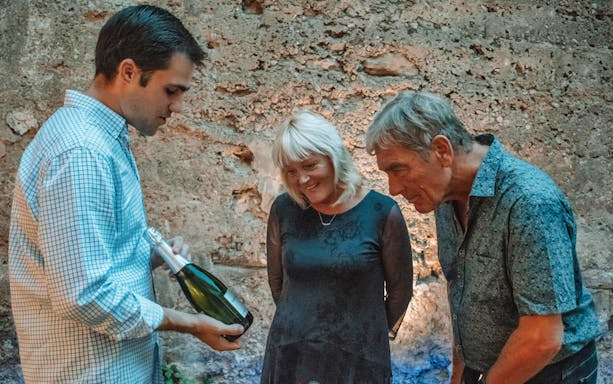 Man presenting wine to two people in Valencia's 11th-century monument.