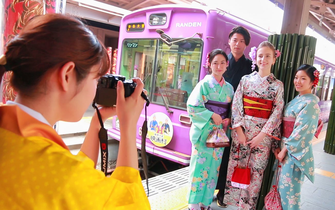 Tourists in kimonos posing for a photo at Randen train station, Kyoto.