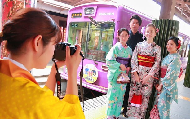 Group in kimonos posing for a photo at Randen train station, Arashiyama, Japan.
