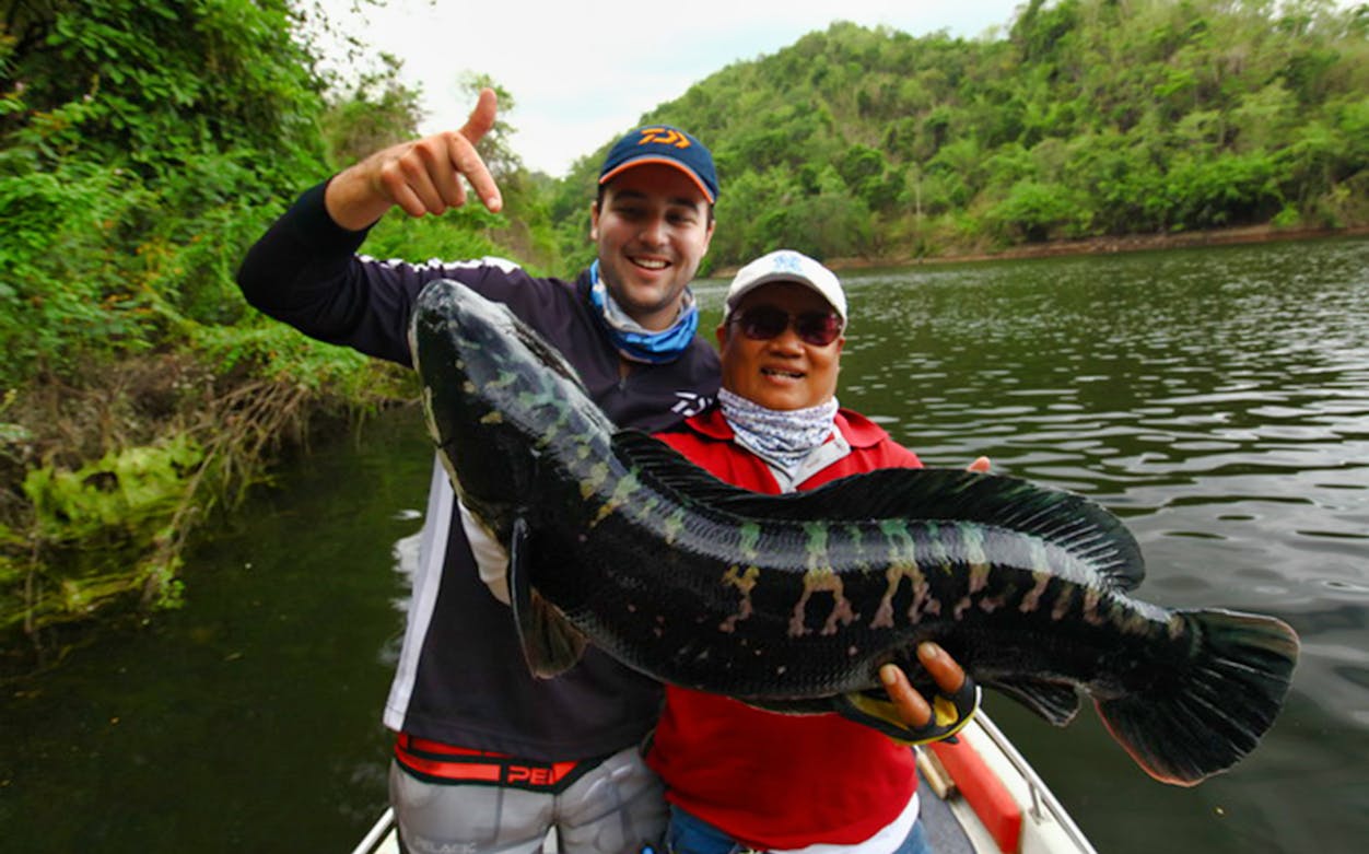 Two people holding a large fish on a boat during a big game fishing adventure tour.