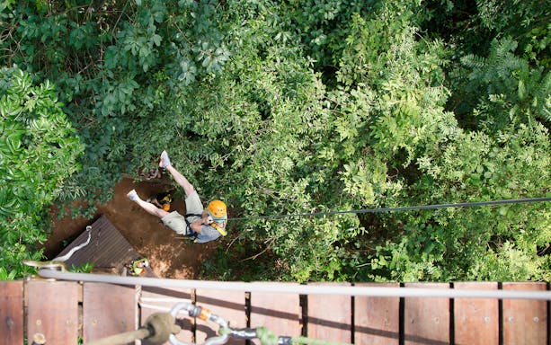 Person ziplining through lush jungle canopy on Jungle Flight Zipline Adventure.