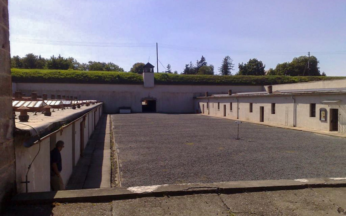 Terezin Concentration Camp courtyard with historical buildings and watchtower, part of a tour from Prague.